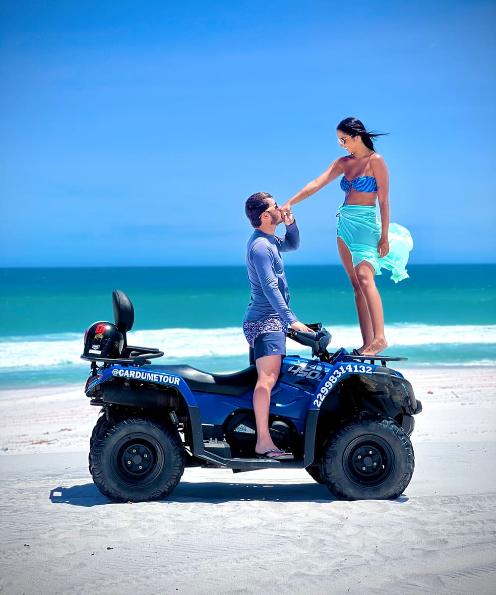 Casal em quadriciclo da Cardumetour com o mar turquesa de Arraial do Cabo ao fundo