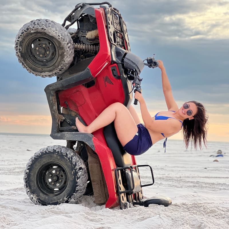 Cliente posando no quadriciclo empinado na praia em dia nublado